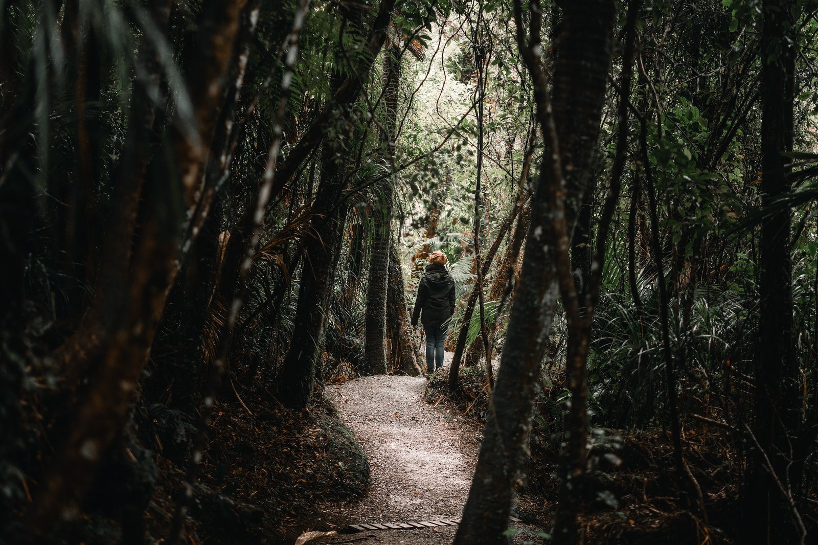 young caucasian girl with brown hat and blue pants walking on the silent and peaceful path that runs